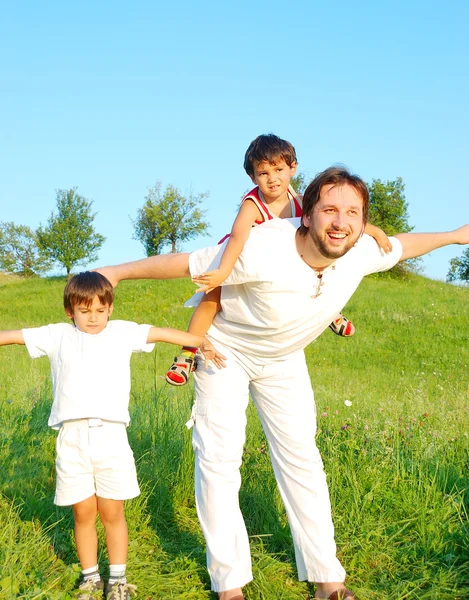 年轻的父亲在与男孩美丽的草地上的白 免版税图库图片
