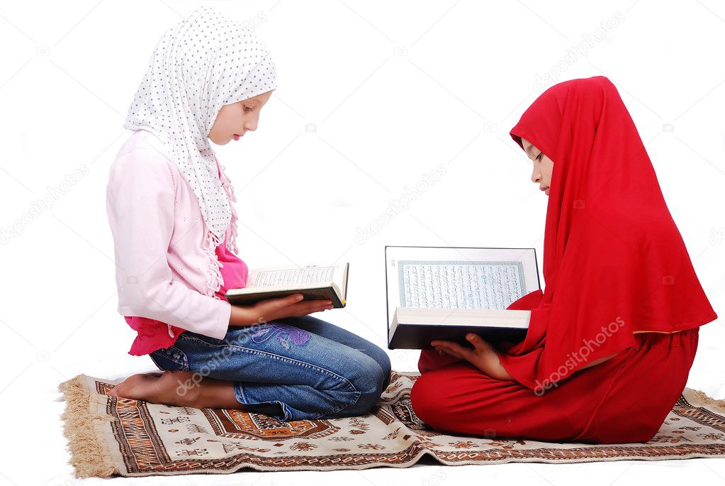 A young muslim girls in traditional clothes reading Koran