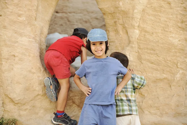 Toeristische zomervakantie, kinderen spelen rond de kleine grot — Stockfoto