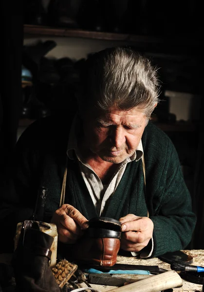 Old man, shoemaker, repairing old handmade shoe in his workshop — Stock Photo, Image