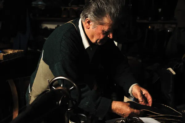 Senior man aan het werk met oude machine in zijn eigen atelier — Stockfoto