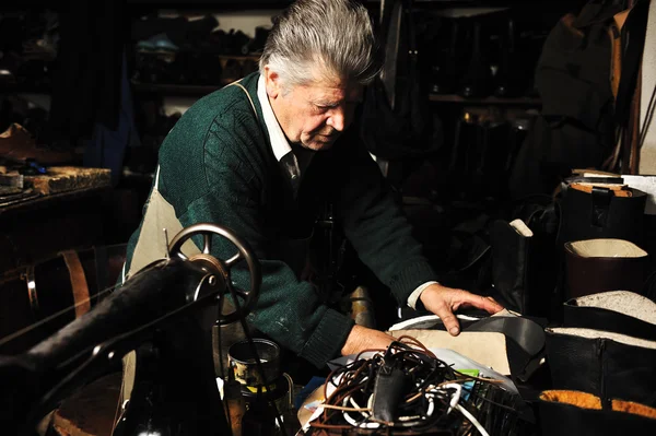 Senior man aan het werk met oude machine in zijn eigen atelier — Stockfoto