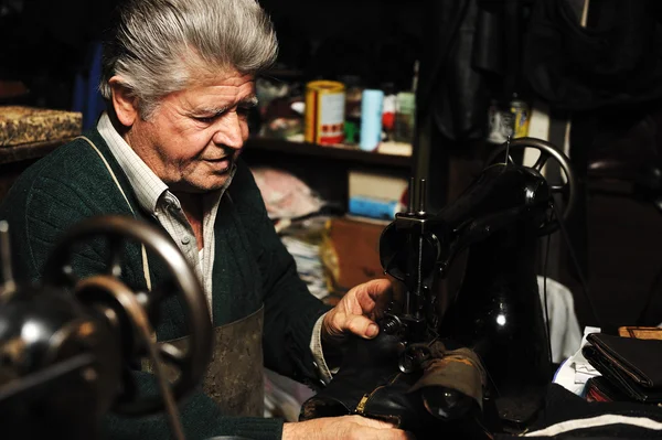 Senior man aan het werk met oude machine in zijn eigen atelier — Stockfoto