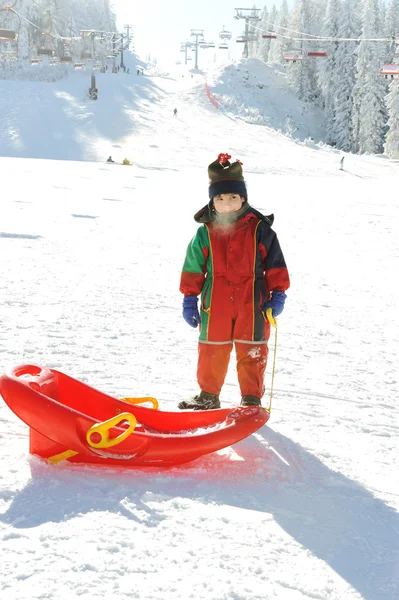 Niño en la nieve con trineo, aliento congelado fuera de su boca — Foto de Stock