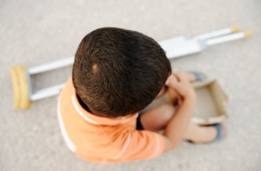 Aç çocuğun bir koltuk değneği ile sokaktaki dilenci