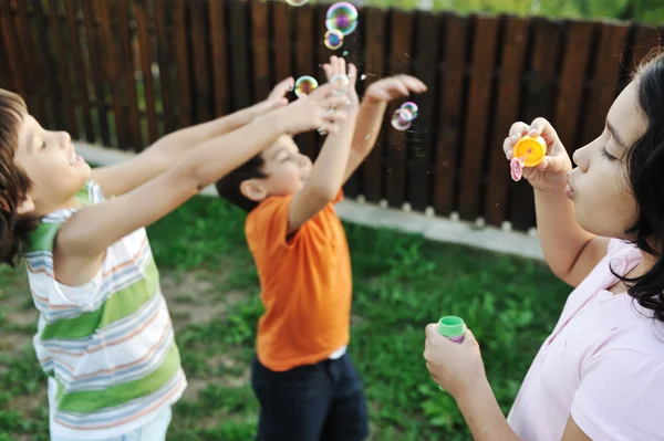 Niños felices jugando con burbujas al aire libre, enfoque selectivo - niños en movimiento — Foto de Stock