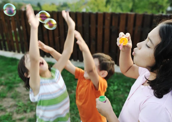 De gelukkige kinderen spelen met bubbels buiten, kids selectieve aandacht - in beweging — Stockfoto