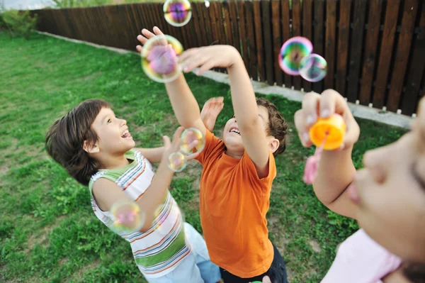 Glückliche Kinder, die draußen mit Blasen spielen, selektiver Fokus - Kinder in Bewegung — Stockfoto