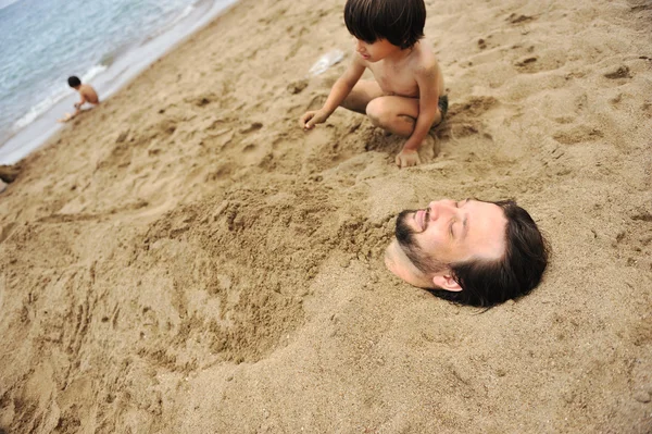 Real happiness, playing on beach: my dad under the sand — Stock Photo, Image