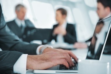 Toplantı sırasında dizüstü bilgisayarda rapor yazarak iş ortamı