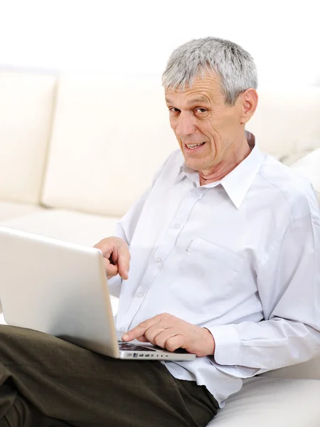 Senior hombre guapo con portátil en casa — Foto de Stock