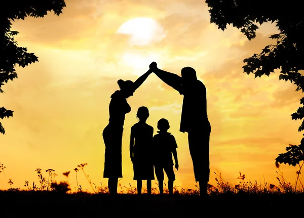 Silhouette, Gruppe fröhlicher Kinder, die auf der Wiese spielen, Sonnenuntergang, Stockfoto