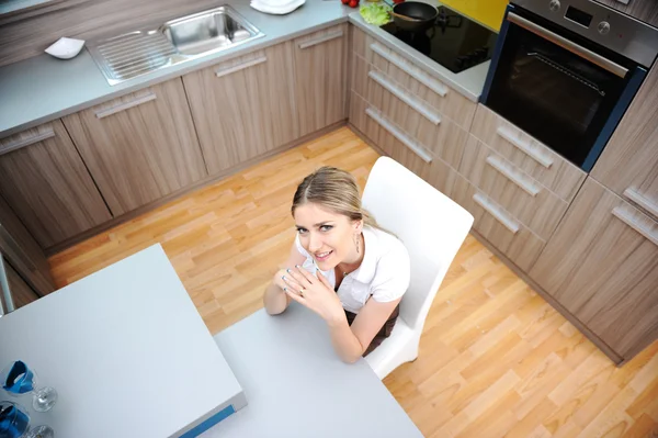 台所の椅子に座っての若い金髪美人 ストック画像