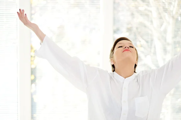 Relaxed young woman at home with raised arms — Stock Photo, Image