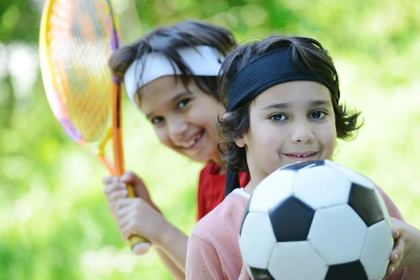 Niños jóvenes con fútbol y tenis afuera — Foto de Stock