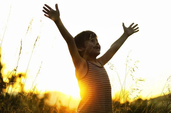 Criança feliz desfrutando na natureza ao pôr do sol — Fotografia de Stock