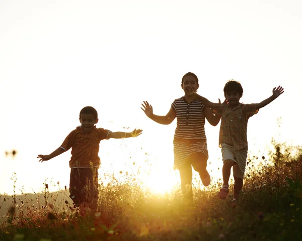 Niños corriendo en el prado al atardecer —  Fotos de Stock