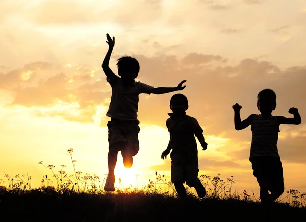 Niños corriendo en el prado al atardecer — Foto de Stock