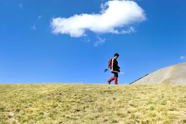 Турист в горах на лугу с небом над головой — стоковое фото