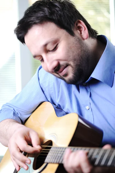 Человек играет на гитаре и расслабляется дома — стоковое фото