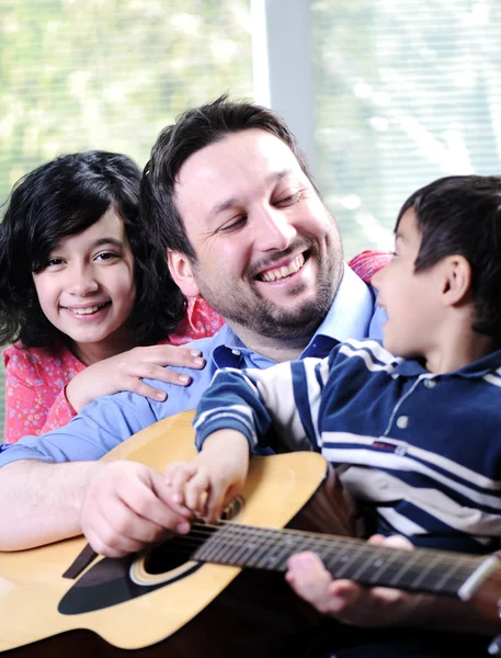 Família feliz tocando guitarra juntos — Fotografia de Stock