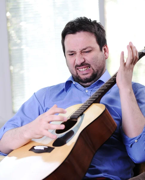 Man playing guitar and singing indoor at sofa — Stock Photo, Image