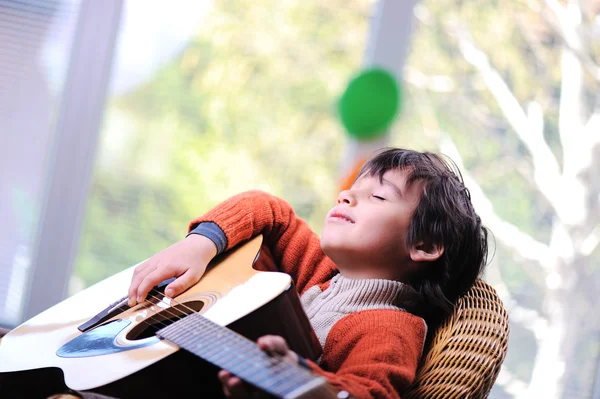 Παιδί παίζει κιθάρα στο σπίτι Εικόνα Αρχείου