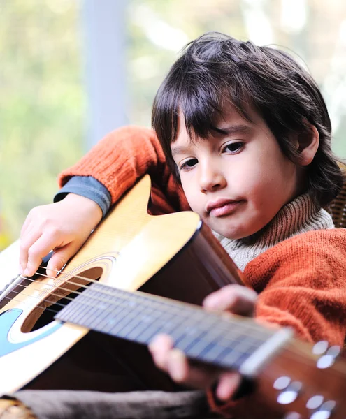 Liten pojke spelar gitarr hemma Royaltyfria Stockbilder