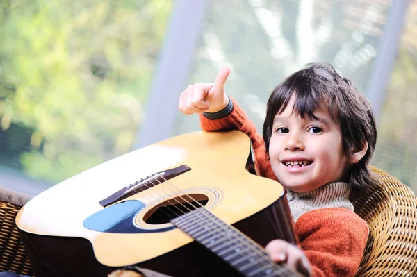 Liten pojke spelar gitarr hemma Royaltyfria Stockbilder
