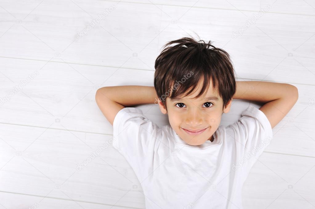 Little boy laying relaxed on white floor at home