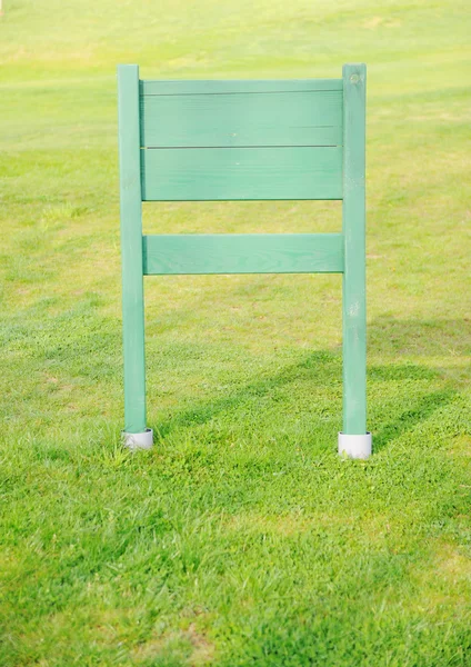 Houten plank voor uw bericht op groen grasveld — Stockfoto