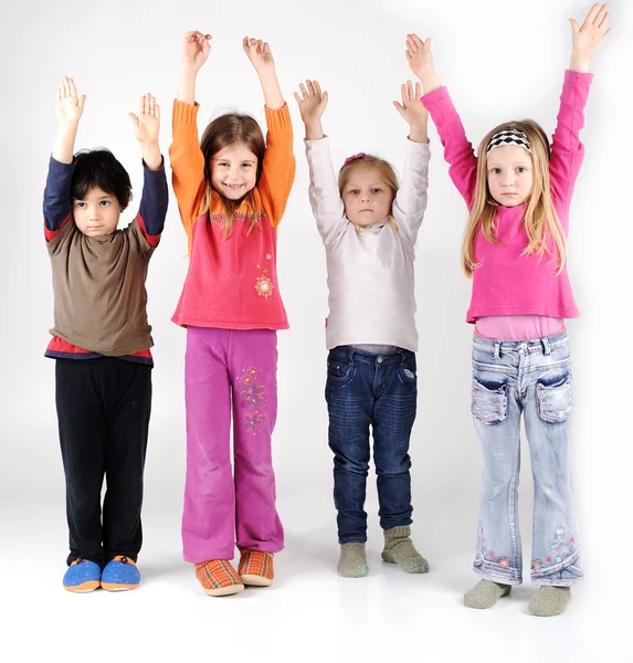 Vier kinderen groep met armen omhoog — Stockfoto