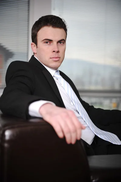 Businessman sitting on sofa in modern office — Stock Photo, Image