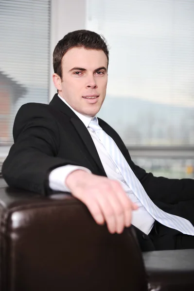 Businessman sitting on sofa in office — Stock Photo, Image