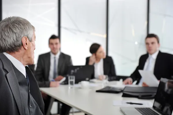 Leitender Geschäftsmann bei einem Treffen. Gruppe von Kollegen im Hintergrund — Stockfoto