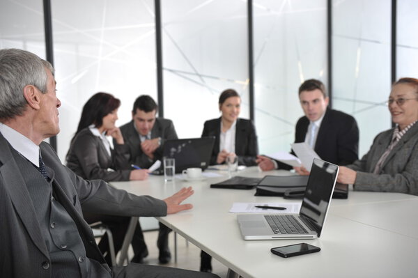 Senior male speaker giving a presentation at a business meeting at office