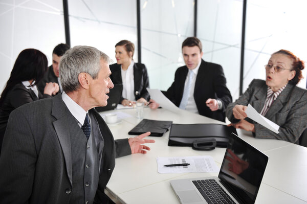 Senior businessman at a meeting. Group of colleagues in the background