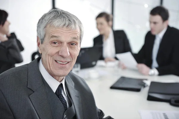 Leitender Geschäftsmann bei einem Treffen. Gruppe von Kollegen im Hintergrund — Stockfoto