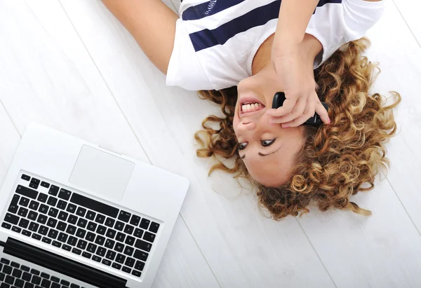 Menina encantadora com laptop e telefone em casa — Fotografia de Stock