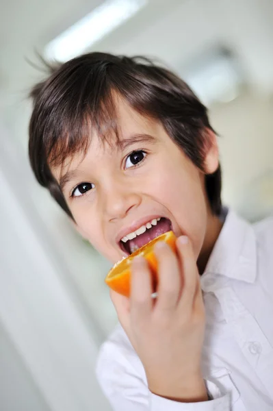 Niño comiendo fruta fresca de naranja — Foto de Stock