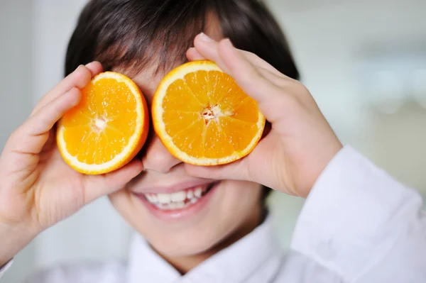 Lilla kid hplaying med orange frukter — Stockfoto