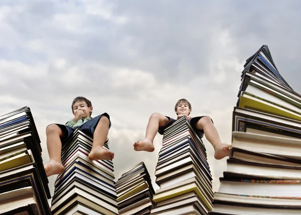 Menino sentado em grande pilha de livros — Fotografia de Stock