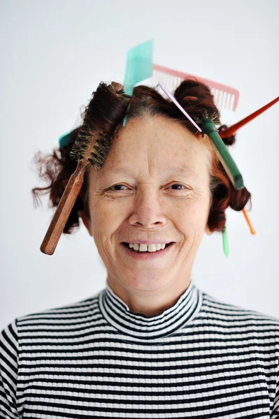 Senior female multitasking with many combs in hair — Stock Photo, Image