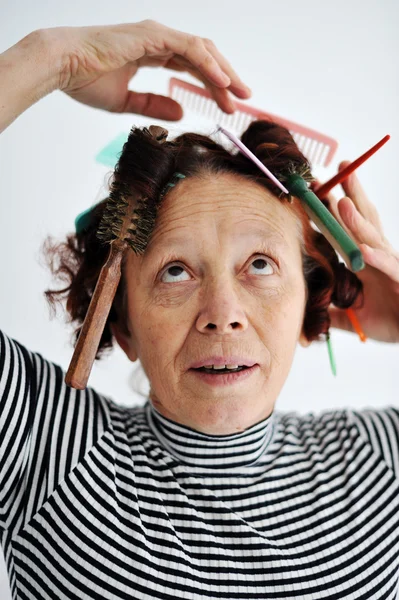 Senior female multitasking with many combs in hair — Stock Photo, Image