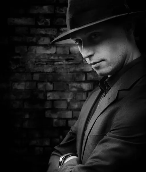 Człowiek z kapelusz stojący na tle cement ciemny — Zdjęcie stockowe