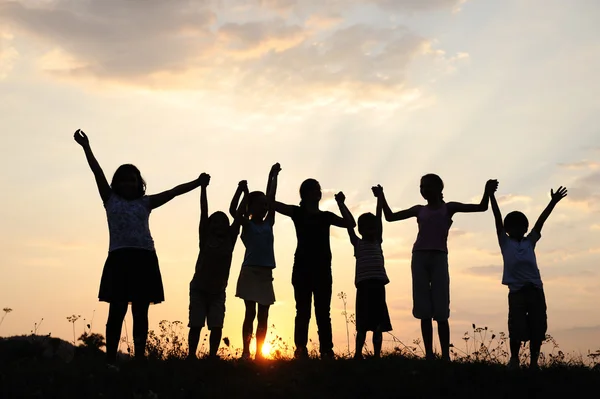 Groupe d'enfants heureux jouant au coucher du soleil d'été — Photo