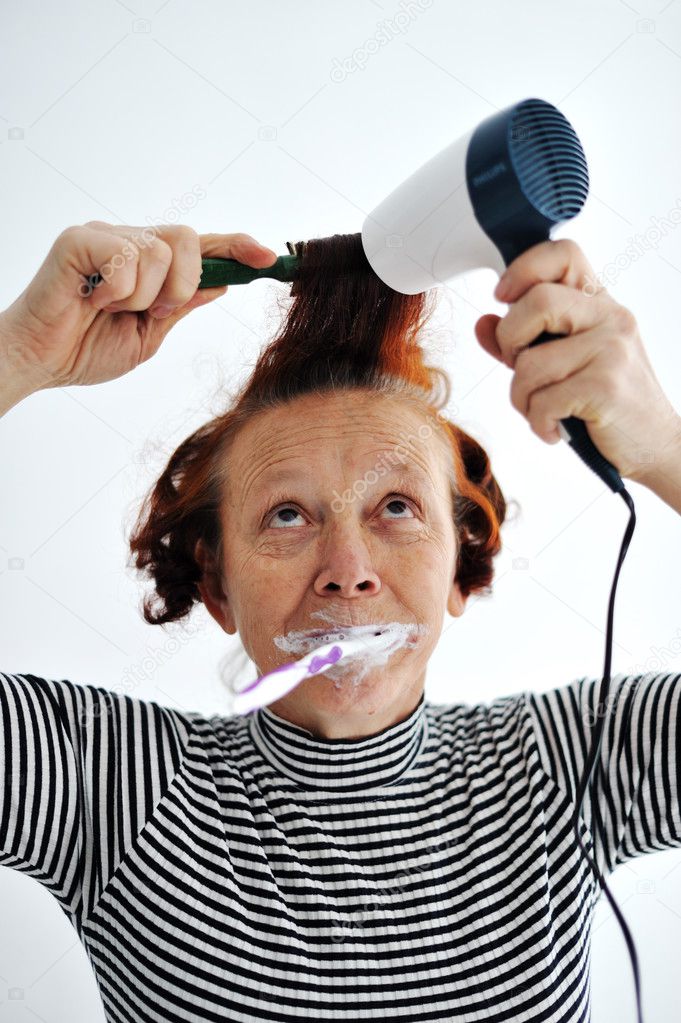 Senior woman brushing teeth and drying hair
