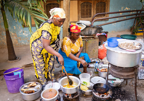African woman cooking traditional food on street
