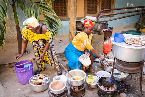 African woman cooking traditional food on street