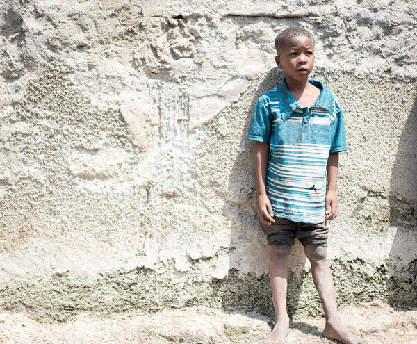 African black boy portrait standing near his poor house
